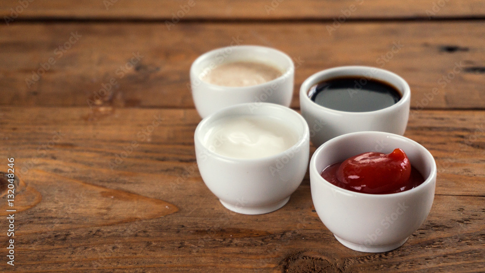 Sauces ketchup, mustard, mayonnaise, sour cream, soy sauce in clay bowls on wooden background Sauces ketchup, mustard, mayonnaise, sour cream, soy sauce in clay bowls on wooden background