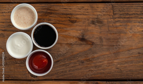 Sauces ketchup, mustard, mayonnaise, sour cream, soy sauce in clay bowls on wooden background