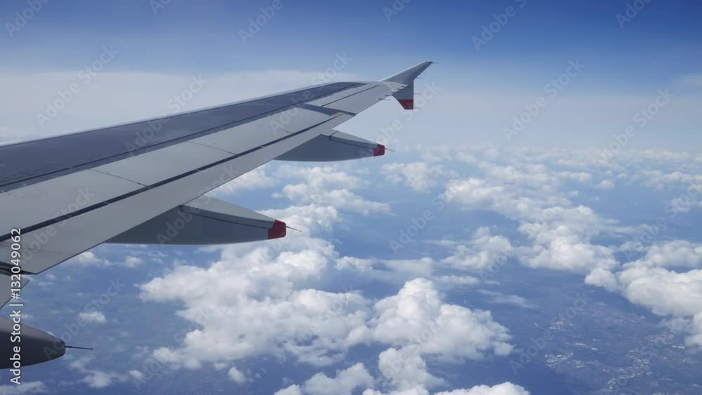 Wing of an airplane flying above the clouds with blue sky. View at the sky from the window of the plane.
Wing of an airplane flying above the clouds with blue sky. View at the sky from the window of the plane.