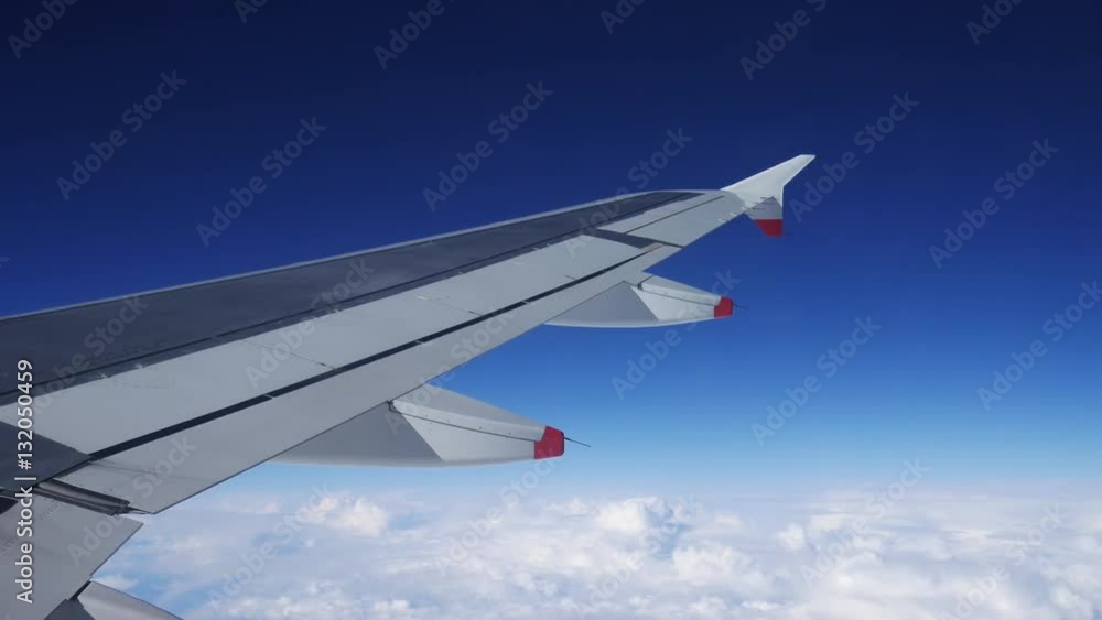 Wing of an airplane flying above the clouds with blue sky. View at the sky from the window of the plane.
Wing of an airplane flying above the clouds with blue sky. View at the sky from the window of the plane.