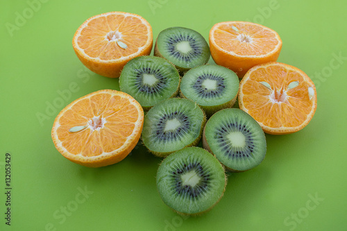 Oranges and kiwis cutted on half on green surface