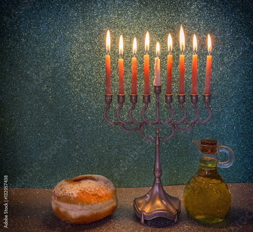 Jewish menorah with candles, sweet donuts and jar of olive oil are traditional symbols for Jewish Hanukkah holiday
