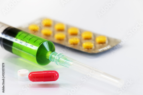 Pills and syringes for treating patients on a white background.