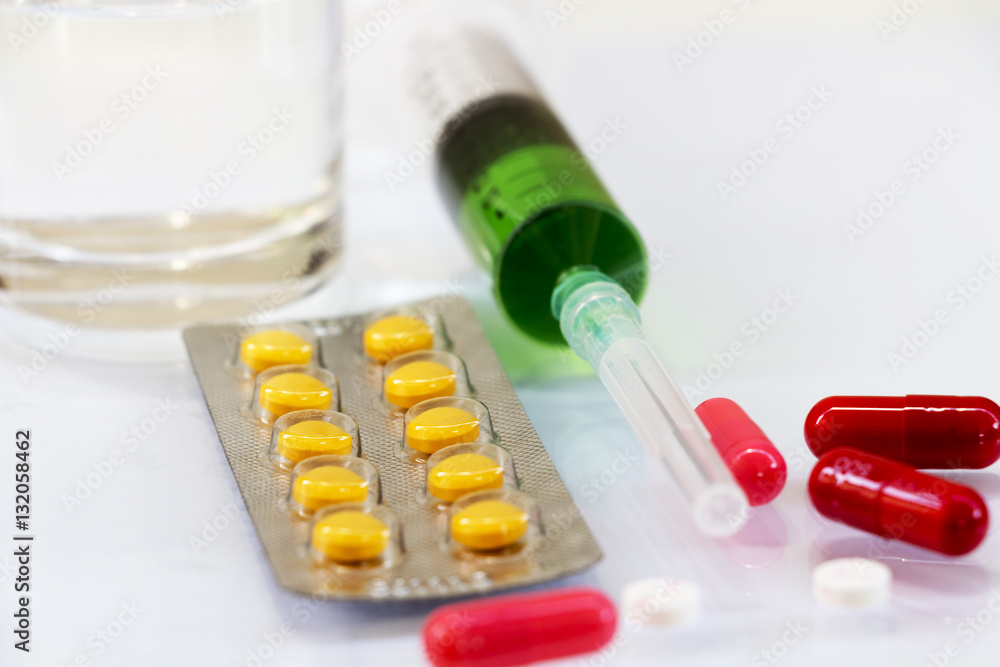 Pills and syringes for treating patients on a white background. Pills and syringes for treating patients on a white background.