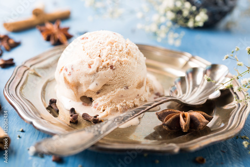 Photography Scoop of homemade ice cream with cinnamon, apple syrup and spices on metal plate on blue wooden background