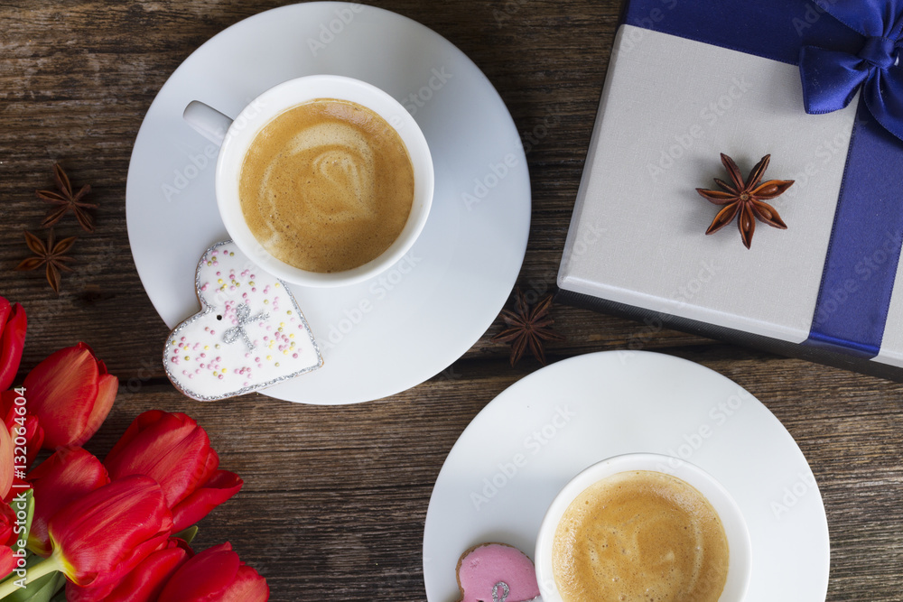 Two cups of Valentines day brewed coffee with fresh red tulips and gift box on wood, top view Two cups of Valentines day brewed coffee with fresh red tulips and gift box on wood, top view