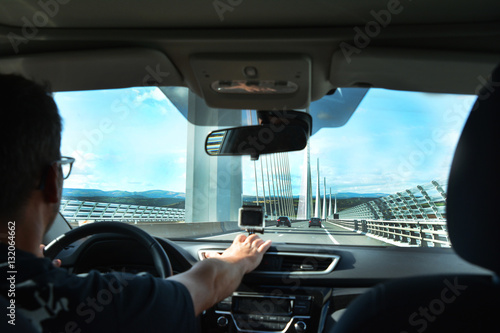 A man in a car traveling on a modern bridge