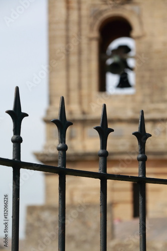 Grates in the foreground and background the bell tower of a church
