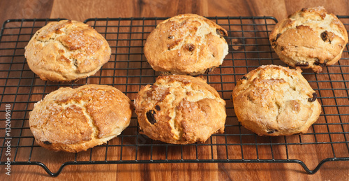 Irish raisin scones cooling on a wire cooling rack, sitting on a wooden cutting board 