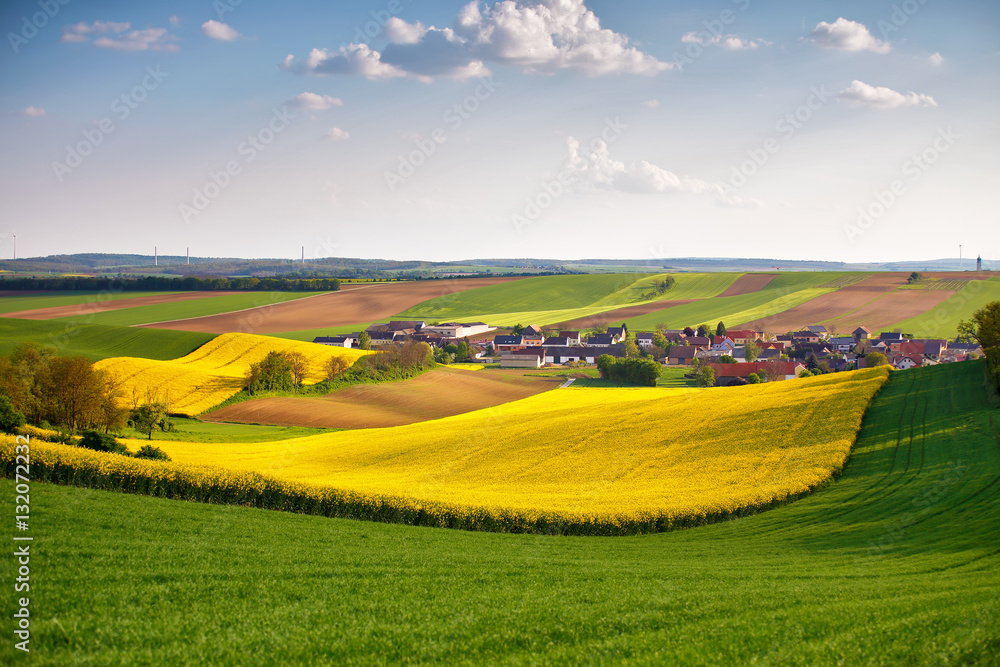 Fototapeta premium Austria spring colza fields. Village on a hills.