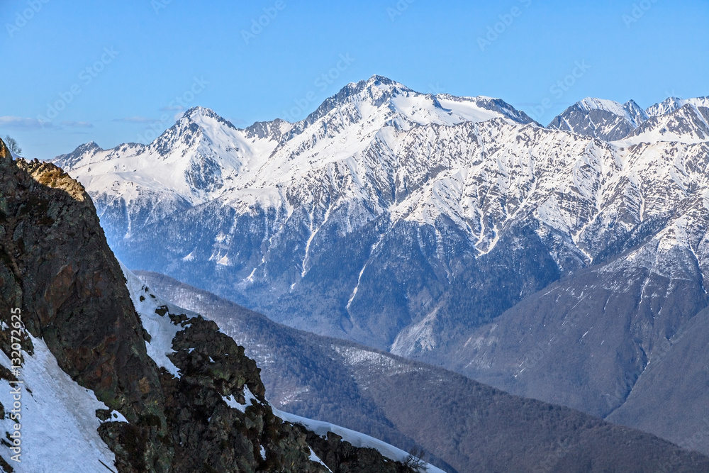 Obraz premium Beautiful mountain scenic winter landscape of the Main Caucasus ridge with snowy peaks and blue sky on a sunny day