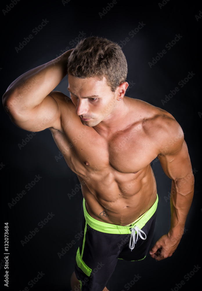 Handsome shirtless bodybuilder smiling at camera on dark, smoky background Handsome shirtless bodybuilder smiling at camera on dark, smoky background