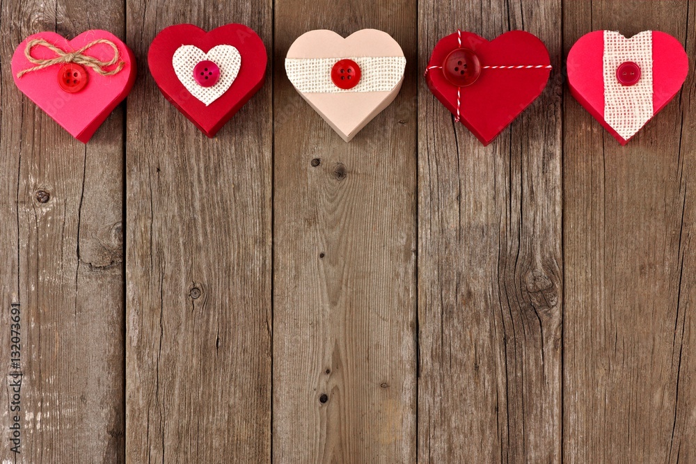 Valentines Day top border of heart shaped gift boxes with red and burlap trim over wood Valentines Day top border of heart shaped gift boxes with red and burlap trim over wood