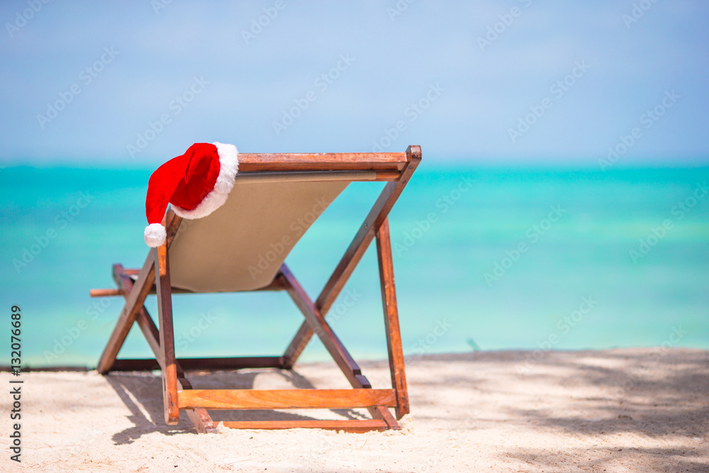 Christmas on the beach - chair with Santa hats at sea. Christmas vacation concept Christmas on the beach - chair with Santa hats at sea. Christmas vacation concept