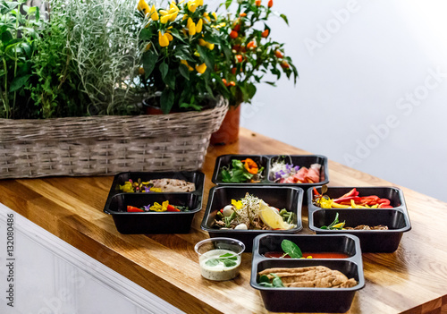 Healthy food and diet concept, restaurant dish delivery. Take away of fitness meal. Weight loss nutrition in foil boxes. Steamed veal with cous and vegetables at wood