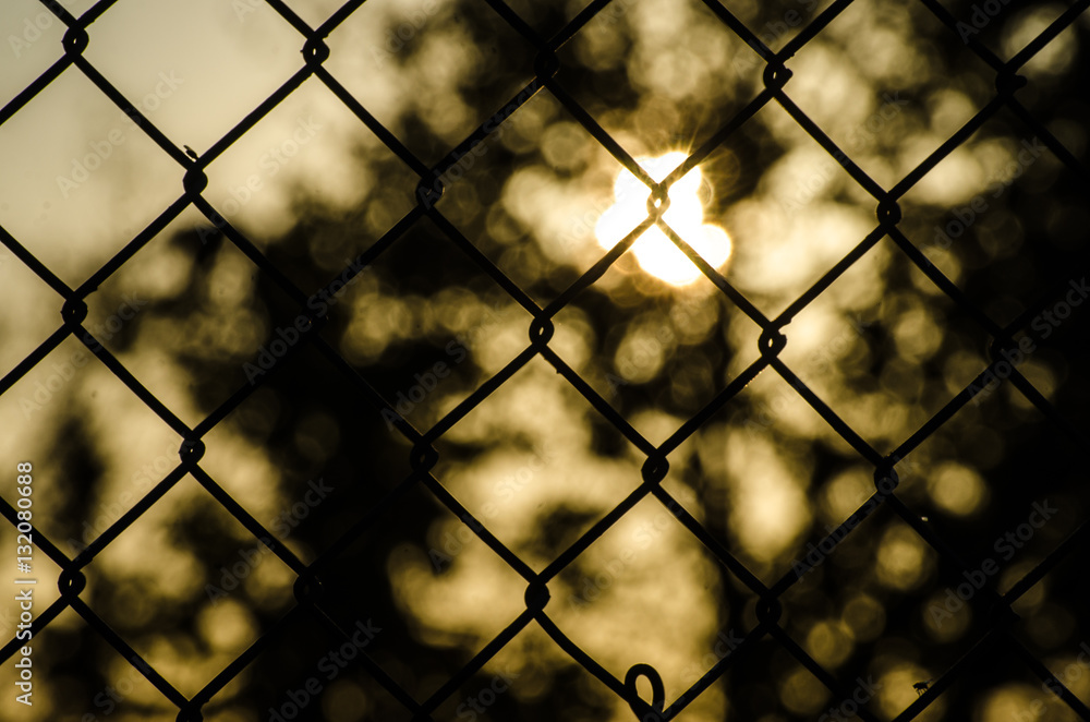 Abstract sun glowing behind a chain link fence close up Abstract sun glowing behind a chain link fence close up