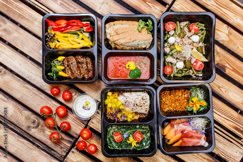 Healthy food and diet concept, restaurant dish delivery. Take away of fitness meal. Weight loss nutrition in foil boxes. Steamed veal with cous and vegetables at wood