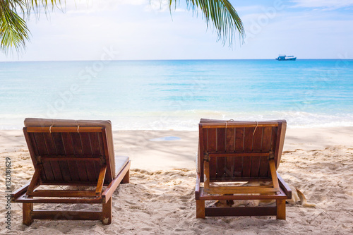 Beach chairs on the white sand beach with blue sky and sun