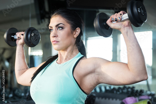 Strong, determined and beautiful woman lifting weights in gym