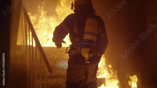 Brave Firefighter Runs Up The Stairs. In Slow Motion. Raging Fire is Seen Everywhere.  Shot on RED EPIC (uhd). photo