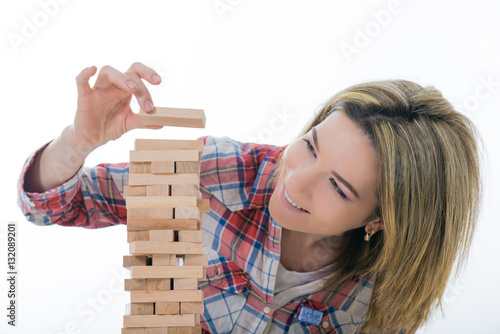 Risk and strategy, planning, hand gambling placing wooden block on tower. Girl builds a pyramid of wooden bars - Jenga game - fun in the office. Girl student plans for future, she believes success
 photo