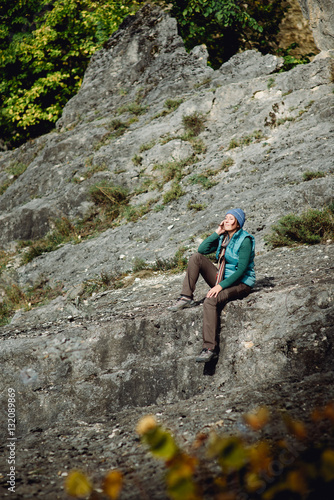 Girl traveler sitting on a large stone background of mountain range