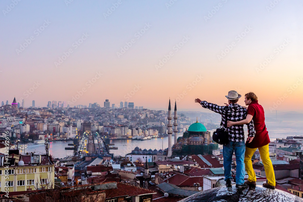 Fototapeta premium Couple travelling together staying on roof and overlooking cityscape