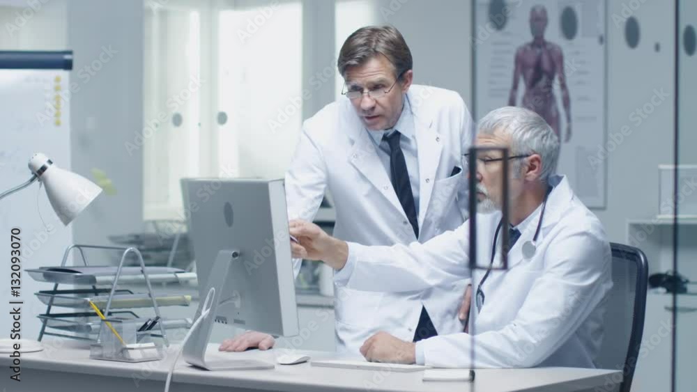 Close-up Portrait of a White Haired Doctor Working on Personal Computer. His Office is Bright and Light. Shot on RED Cinema Camera in 4K (UHD). Close-up Portrait of a White Haired Doctor Working on Personal Computer. His Office is Bright and Light. Shot on RED Cinema Camera in 4K (UHD).