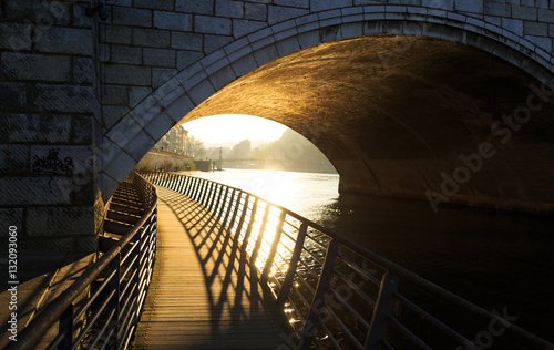 Walkway under a bridge over the Saone river in Lyon, on a sunny afternoon.