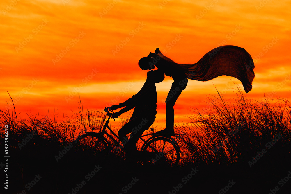Silhouette couple kissing on bike over sunset background.