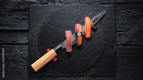 Sushi served on japanese knife on a black slate plate