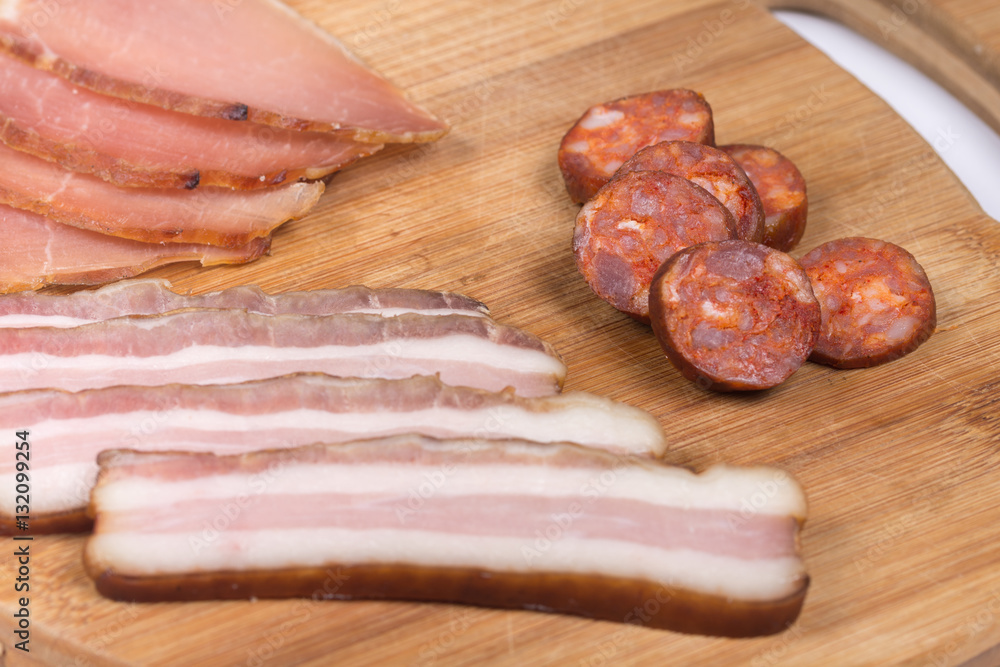 Sliced smoked bacon and sirloin on the wooden board Sliced smoked bacon and sirloin on the wooden board