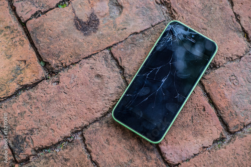 Broken screen glass of mobile smartphone on the brick floor