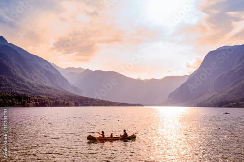 Family rowing in canoe boat on beautiful lake Bohinj at sunset, located in the Bohinj valley of Julian Alpsin in Triglav national park, Slovenia. photo