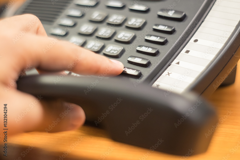 businessman dialing voip phone in the office, keyboard and monitor detail in the background with vintage color tone effect businessman dialing voip phone in the office, keyboard and monitor detail in the background with vintage color tone effect