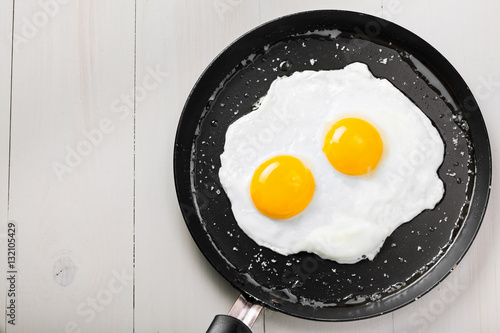 Traditional healthy easy quick breakfast meal made of two fried eggs served on a frying pan. International simple food, top view.