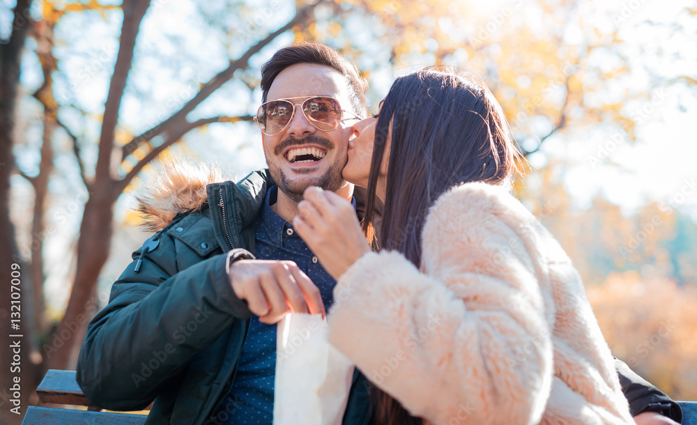 Loving couple sitting on the bench in the park and eating popcor Loving couple sitting on the bench in the park and eating popcor