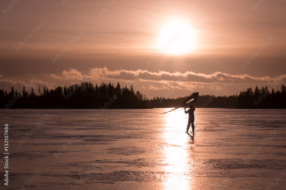 Kitewing skier at a frozen lake during sunset