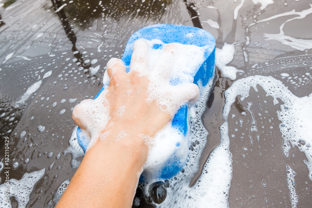 Fototapeta premium Close up of Hand Washing Brown Car with Blue Sponge and Bubbles (Foam) - motion blur