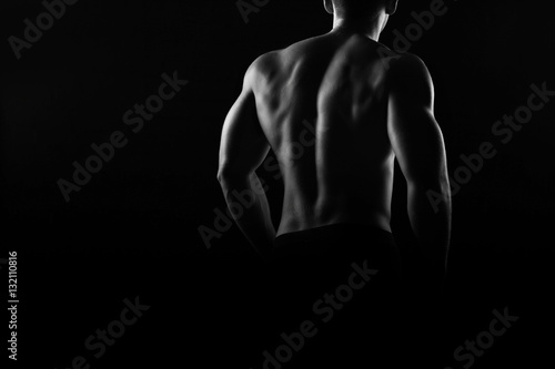 Muscular man bodybuilder. Man posing on a black background, shows his muscles. Bodybuilding, posing, black background, muscles - the concept of bodybuilding. Article about bodybuilding.
