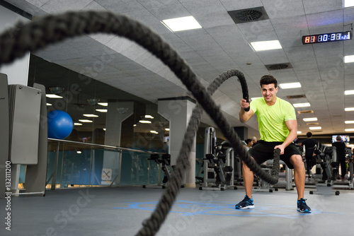 Fotografia Man with battle ropes exercise in the fitness gym.