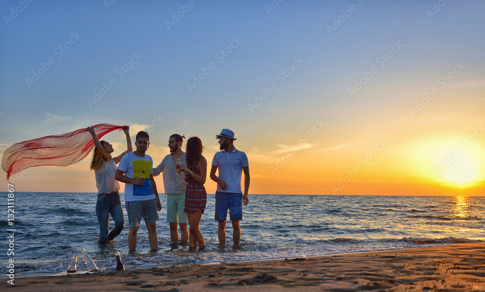 Fototapeta premium group of happy young people dancing at the beach on beautiful summer sunset