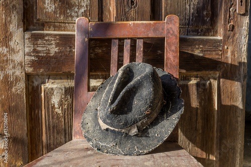 Battered old hat damaged by clothes moth on vintage background. A forgotten hat covered with spider web among the ruins of a house. Imagine the owner of this hat and tell their story.