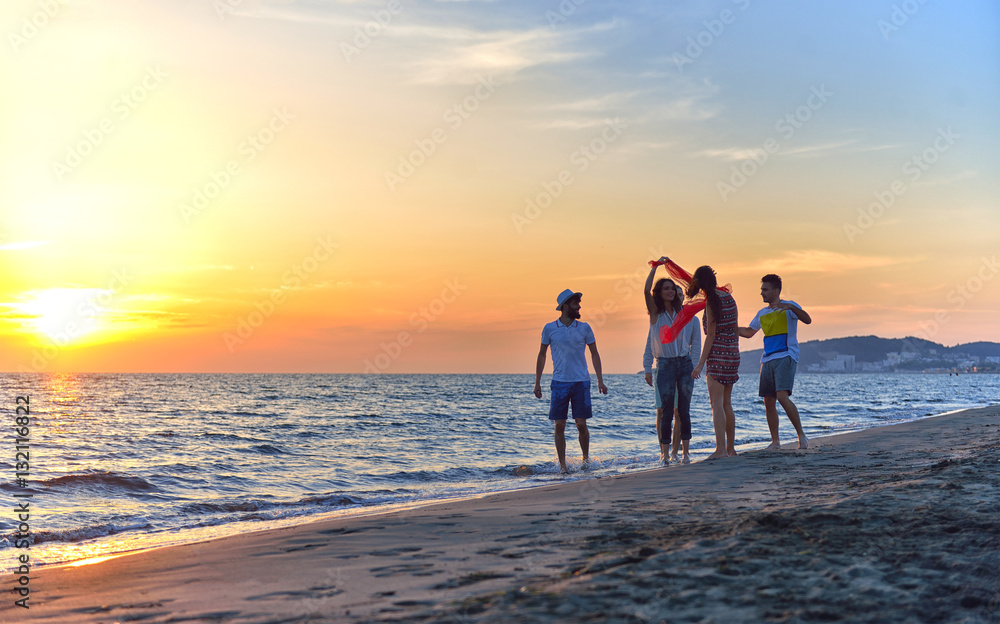 Fototapeta premium group of happy young people dancing at the beach on beautiful summer sunset