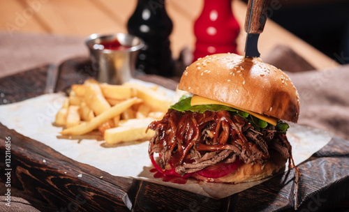 Close up of big burger being served with French fries photo