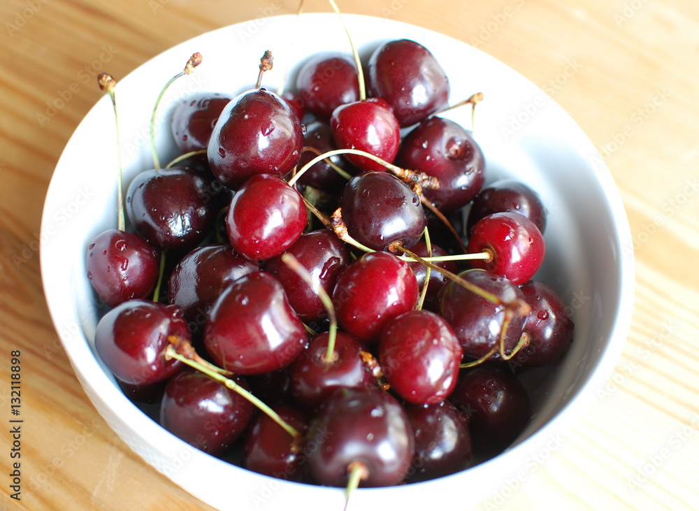 Cherry berries with water drops in the bowl on wood background Cherry berries with water drops in the bowl on wood background