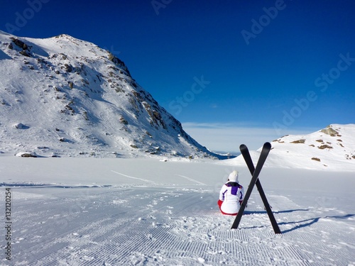 GIRL AND SKI EQUIPMENT ON THE FROZEN LAKE IN THE MOUNTAINS COVERED WITH SNOW DOMAIN OF 4 VALLEYS , VERBIER , VALAIS, SWISS