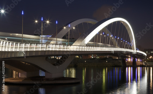 Tram speeding over illuminated bridge Raymond Barre in Lyon at night.