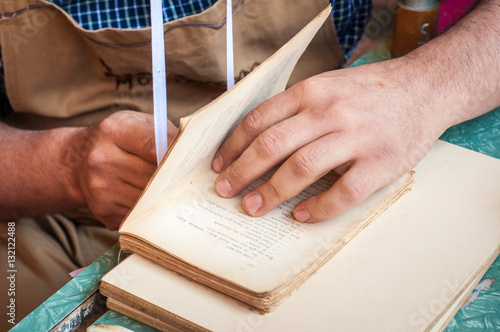 фотографія Bookbinding. Male worker binding pages.