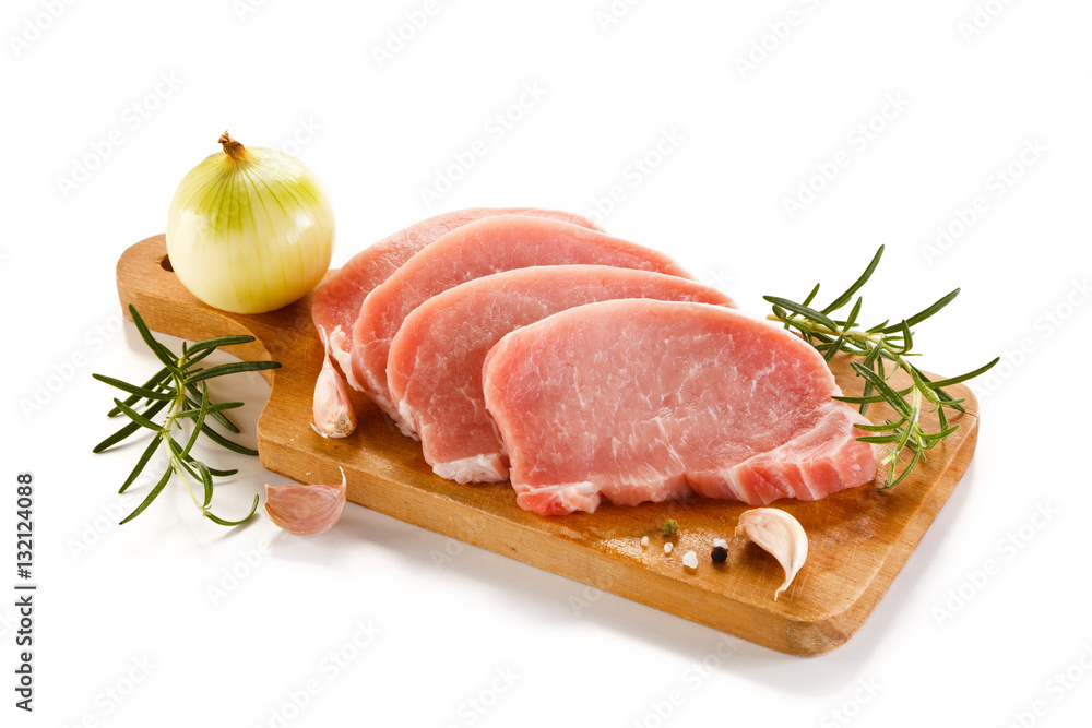 Raw pork chops on cutting board and vegetables Raw pork chops on cutting board and vegetables